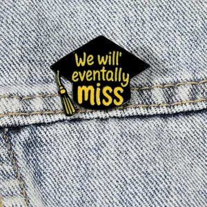 Graduation cap enamel brooch with yellow tassel and text on blue denim fabric