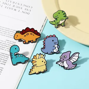 Set of six colorful cartoon dinosaur enamel pins displayed on a decorative tray