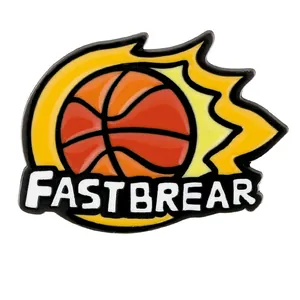 Spilla creativa in smalto con palla da basket e fiamme gialle su sfondo bianco neutro