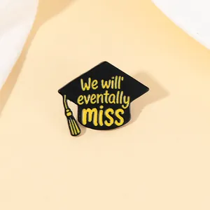Macro detail of alloy graduation brooch with black cap, yellow tassel and quote text