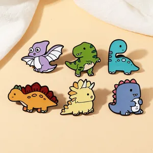 Detail of six cartoon enamel dinosaur pins including T-Rex and Triceratops on beige background