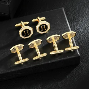 Detalle de gemelos octogonales dorados con letra H negra y diamantes incrustados
