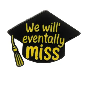 Black enamel graduation cap brooch with yellow text and tassel on a white background