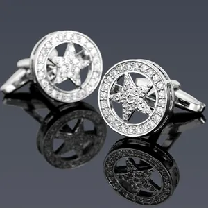 Macro shot of silver star-shaped cufflinks with cubic zirconia on black reflective surface