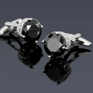 Detail of silver cufflinks with black round zircon and ornate hollow base design