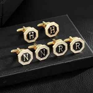 Gemelos octagonales dorados con incrustación negra y cristales con letras H N R