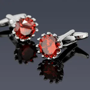 Detalle de gemelos plateados con cristal rojo redondo y engaste de corona elegante