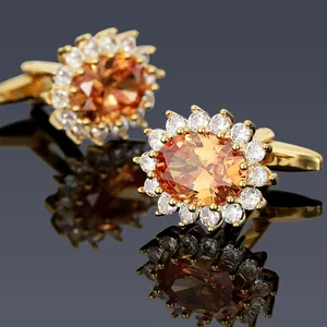 Close-up of luxury gold cufflinks with amber oval stone and white zircon halo detail