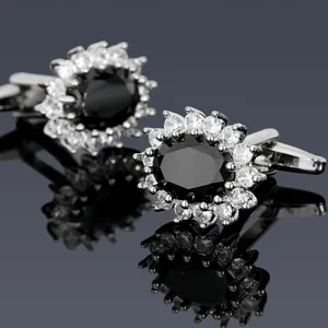 Macro shot of cufflinks featuring oval black gemstones with crystal halo on mirror surface