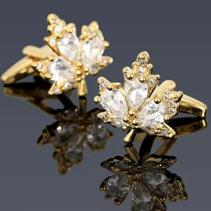 Détail de boutons de manchette feuille d'érable dorés avec zircons sur miroir noir