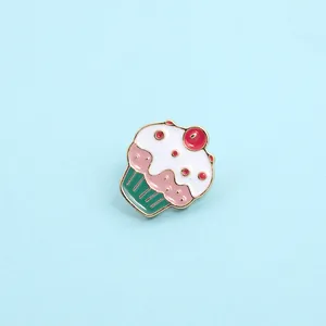 Detailed close-up of a cute enamel cupcake brooch with pink cream and gold outlines
