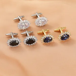 Detailed view of three pairs of halo-set oval crystal cufflinks on peach silk fabric