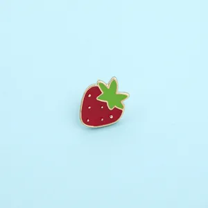Close-up of strawberry enamel brooch pin with red finish and gold-tone metal details