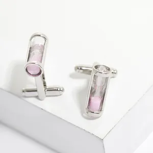 Boutons de manchette sablier argentés créatifs avec sable rose sur socle blanc