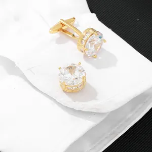 Elegant gold round cufflinks with clear cubic zirconia on a white dress shirt sleeve
