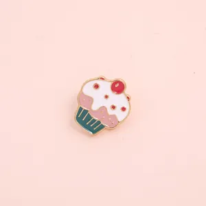 Close-up of a colorful cupcake enamel pin with gold plating and sweet cherry detail