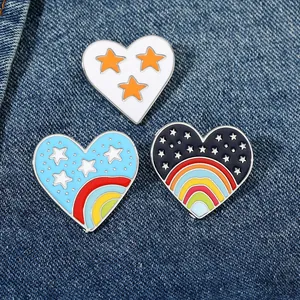 Détail de broches en cœur émaillé avec étoiles et arcs-en-ciel sur fond en denim