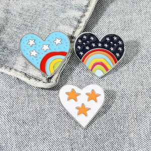 Vue détaillée des pin's émaillés cœur arc-en-ciel et badges étoiles sur du denim