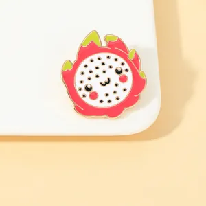 Close-up of a cartoon dragon fruit enamel pin with a cute face on a ceramic plate