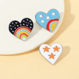 Détail macro de trois pins en émail en forme de cœur aux motifs d'arc-en-ciel et étoiles
