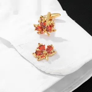 Boutons de manchette feuille d'érable dorés avec pierres rouges sur une manchette blanche