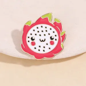 Macro detail of cute dragon fruit enamel brooch with cartoon face and gold plating