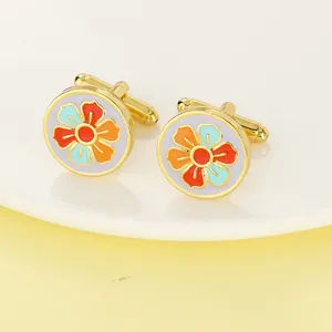 Detailed close-up of gold round cufflinks with colorful enamel floral pattern on ceramic