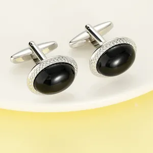 Dettaglio di gemelli ovali in cristallo nero con cornice in metallo intrecciato