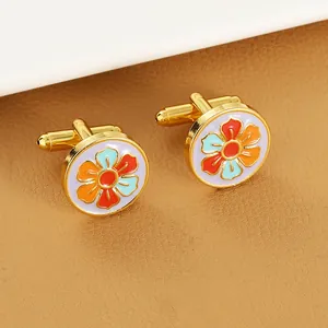 Detail view of round enamel cufflinks with colorful floral pattern and golden finish