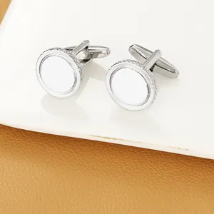 Detail of silver round cufflinks with white enamel inlay and textured woven border edges