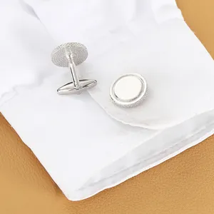 Classic silver round cufflinks with knurled edges on a white shirt sleeve