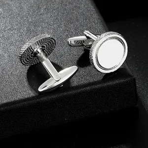 Pair of polished silver round cufflinks with textured edges on a black display box