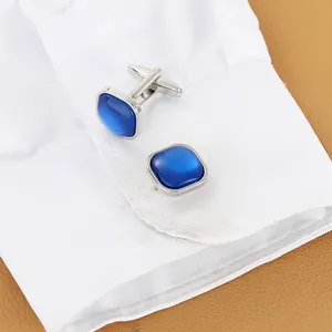 Square silver-tone cufflinks with deep blue crystals on white shirt sleeve for men