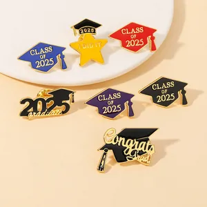 Detail view of 2025 graduation enamel pins featuring doctoral caps and gold metal badges