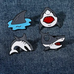 Lot de quatre pin's en émail requin dessin animé sur fond en tissu denim bleu