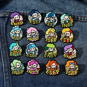 Collection of 16 colorful MBTI personality enamel pins displayed on blue denim fabric