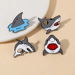 Lot de quatre pin's en émail de requins cartoon avec aileron et motifs de sauts en métal