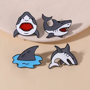 Lot de quatre épingles en émail de requin présentées sur un support en marbre blanc