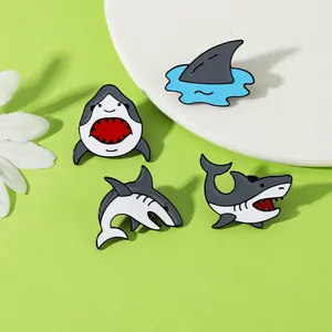 Vue détaillée de quatre pin's requin en émail aux poses variées sur fond vert clair
