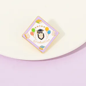 Detail of graduation enamel pin with mortarboard and balloons on white ceramic