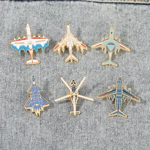 Set of 6 metal aircraft enamel pins including J-20 fighter and H-6 bomber on denim fabric
