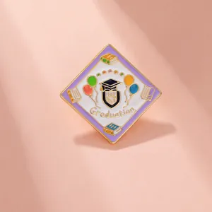 Detail of graduation enamel pin featuring a mortarboard, books, and colorful balloons
