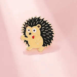 Detailed view of a cute cartoon hedgehog enamel pin with golden metal edges and a smile