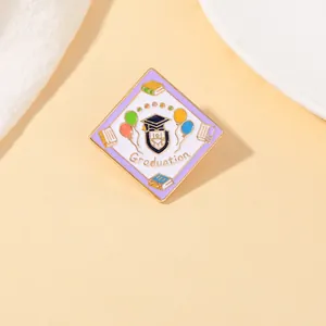 Macro detail of square Graduation enamel pin with golden frame and colorful balloon motifs
