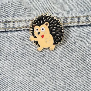 Cute cartoon hedgehog enamel pin with golden metal edge on a blue denim jacket background