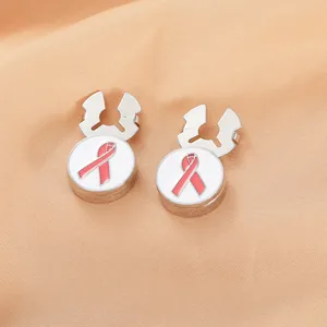 Macro shot of silver cufflinks featuring pink ribbon enamel design on orange satin fabric