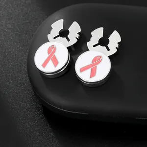 Macro detail of silver cufflinks featuring pink ribbon emblem on white enamel background