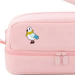 Cartoon white bird enamel pin with yellow scarf on pink bag accessory decor