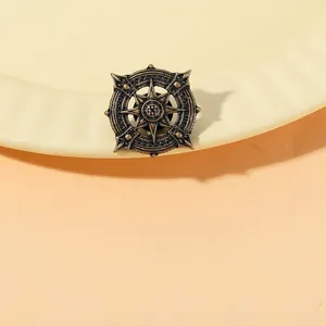 Detailed close-up of a vintage bronze compass brooch with intricate relief engraving