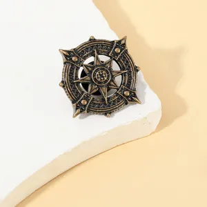 Macro shot of vintage bronze nautical anchor brooch on a textured white stone base